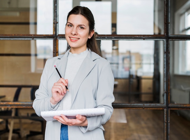 Free photo happy businesswoman looking at camera with holding pencil and diary