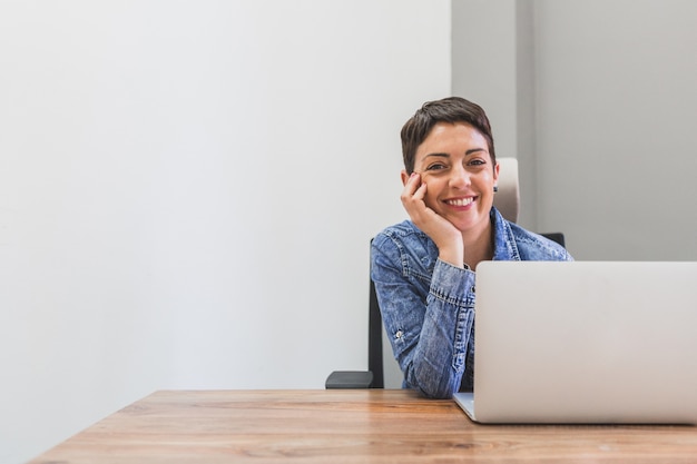 Happy businesswoman posing next to her laptop