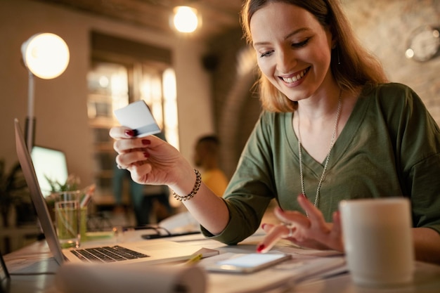 Free photo happy businesswoman using smart phone and credit card while shopping on the internet at night the office