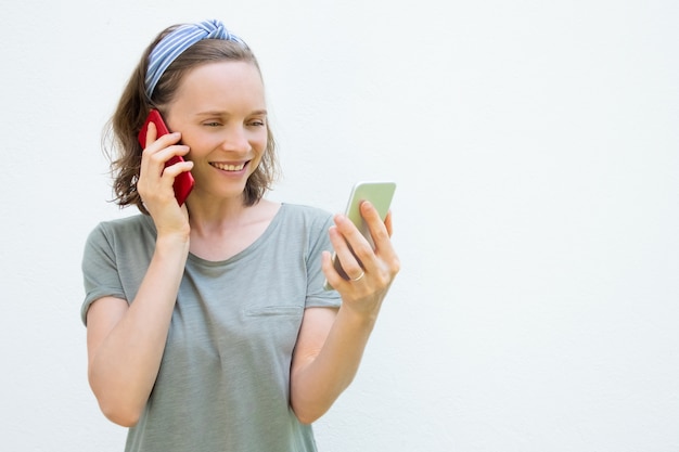 Happy busy young woman using two mobile phones