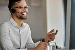 Free photo happy call center agent using computer while communicating with clients and working in the office