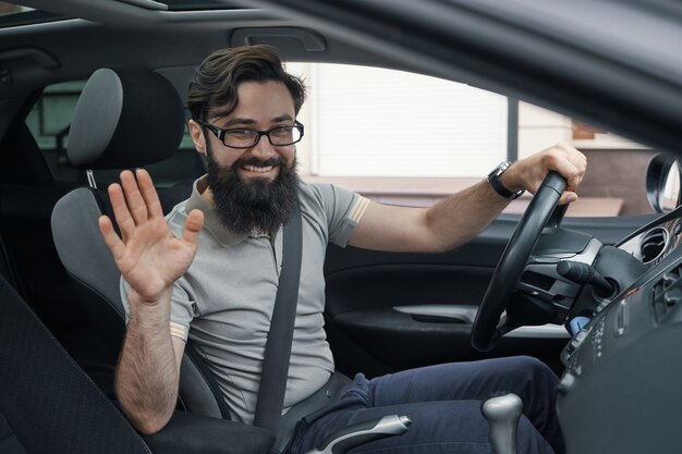 Happy car driver with fastened seat belt waving