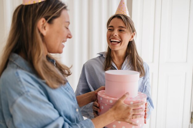 Free Photo happy caucasian mother giving birthday present to blonde teenage daughter isolated on white background. holidays, celebration and women concept.