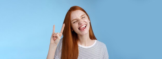 Happy cheerful carefree chilling redhead teenage girl having fun stick tongue close eyes dancing