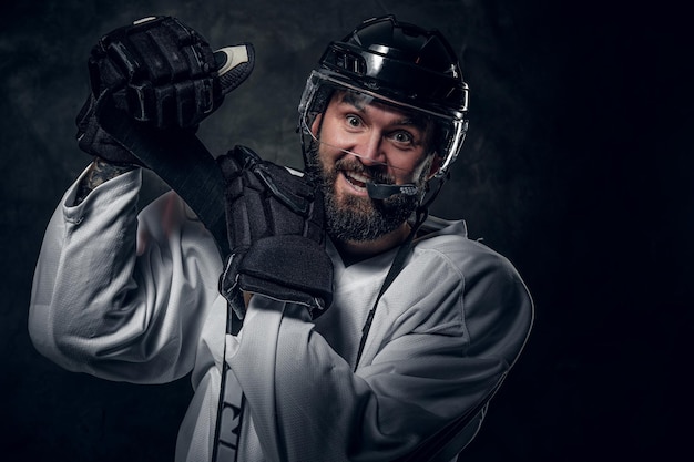 Free photo happy cheerful hockey player has a photo session at dark photo studio.