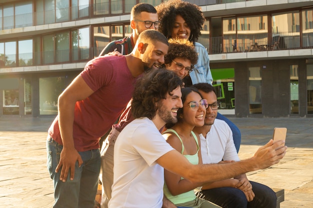 Happy cheerful interracial people taking group selfie