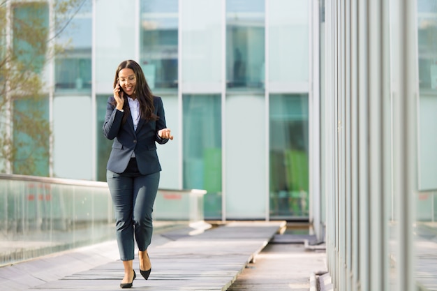 Happy cheerful Latin businesswoman talking on phone