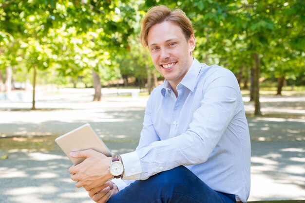 Happy cheerful young businessman with tablet