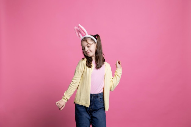 Free photo happy cheery junior dancing around in the studio with fluffy bunny ears