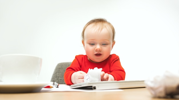 Happy child baby girl sitting with keyboard of modern computer or laptop isolated on a white studio.