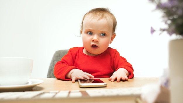 Free photo happy child baby girl sitting with keyboard of modern computer or laptop in white