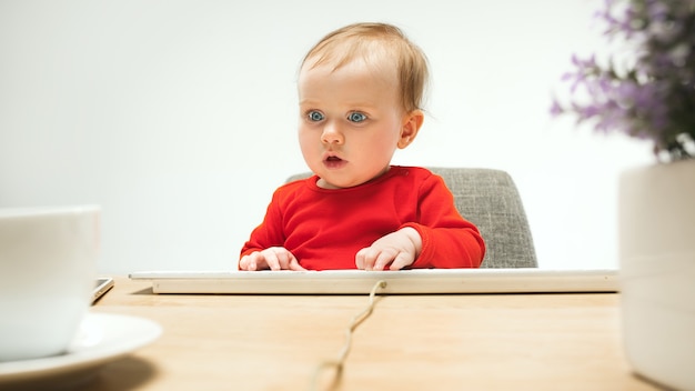 Free photo happy child baby girl toddler sitting with keyboard of computer isolated on a white