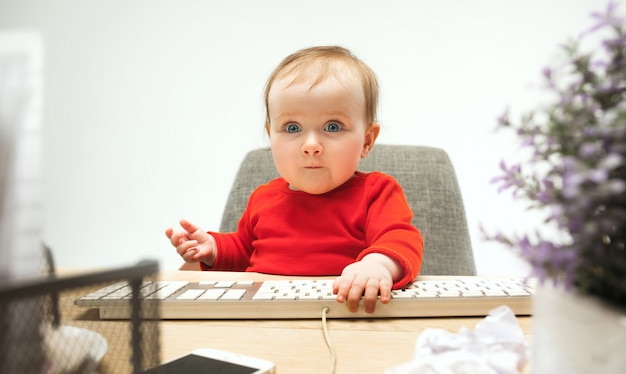 Free photo happy child baby girl toddler sitting with keyboard of computer isolated