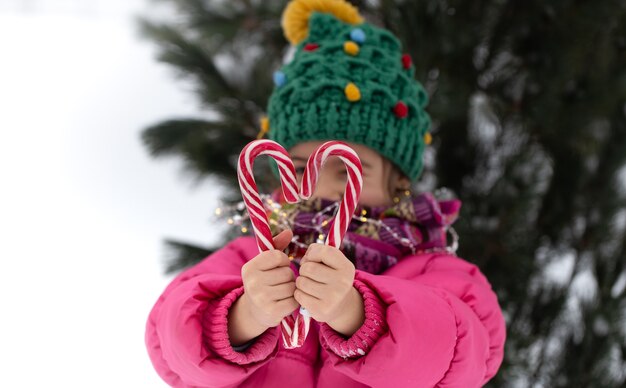 Happy child with a big candy canes under a christmas tree. Winter holidays concept.