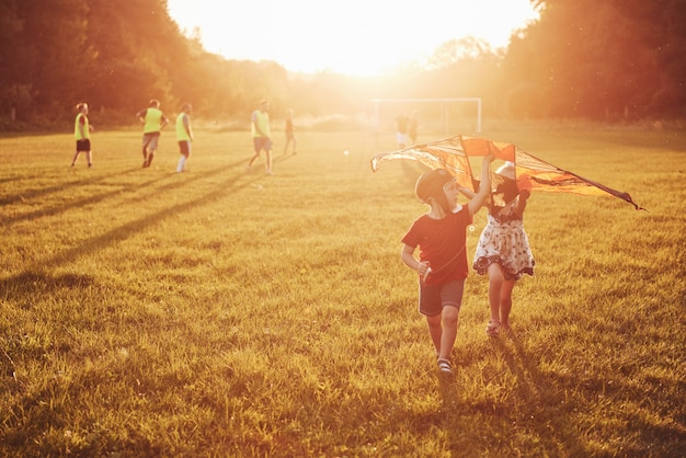 Free photo happy children launch a kite in the field at sunset. little boy and girl on summer vacation