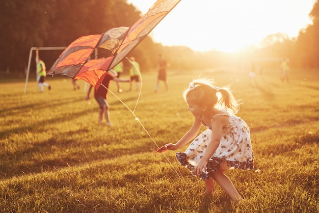 Free photo happy children launch a kite in the field at sunset. little boy and girl on summer vacation