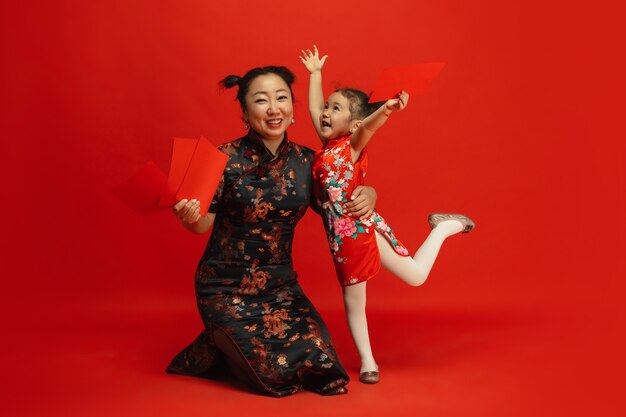 Happy Chinese New Year. Asian mother and daughter portrait isolated on red