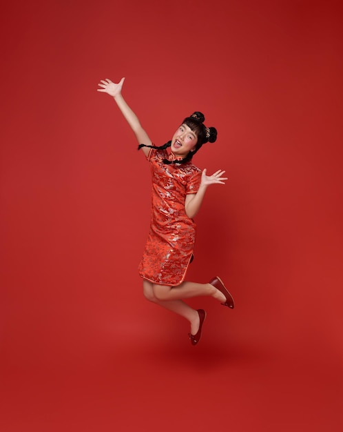 Happy Chinese new year Happy smiling children asian girl wearing traditional qipao dress jumping celebrate isolated on red background