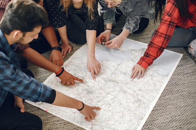 Free Photo happy circle of friends planning a trip. globe trotters inspecting a map being at home. european and indian ethnicity.