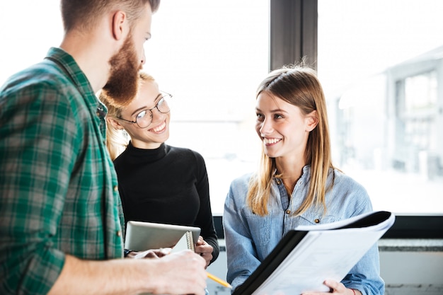 Happy colleagues in office talking with each other holding folder