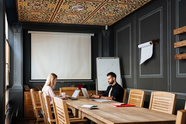 Happy colleagues sitting near coffee while work with laptops