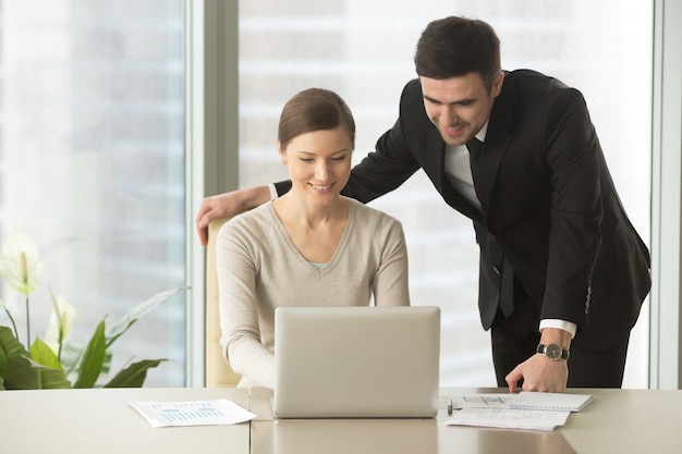 Happy company employees using laptop in office