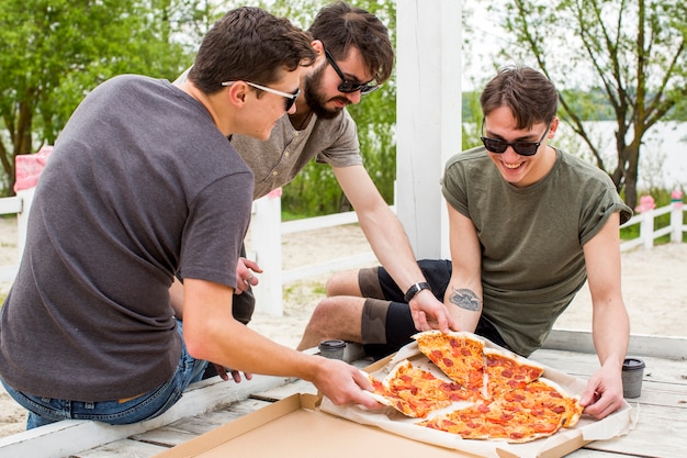 Free photo happy company with pizza resting in nature