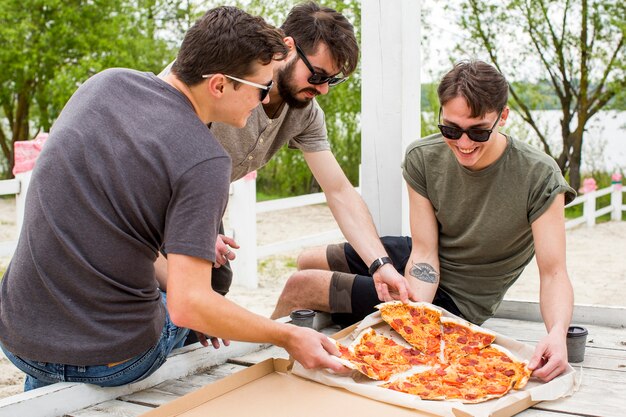 Happy company with pizza resting in nature