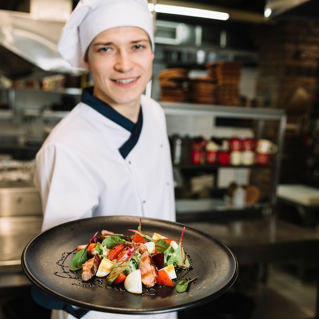 Happy cook showing salad with meat on plate