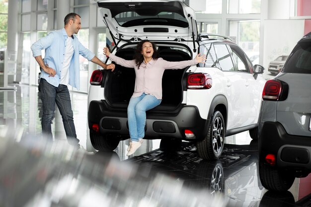 Happy couple in car showroom dealership