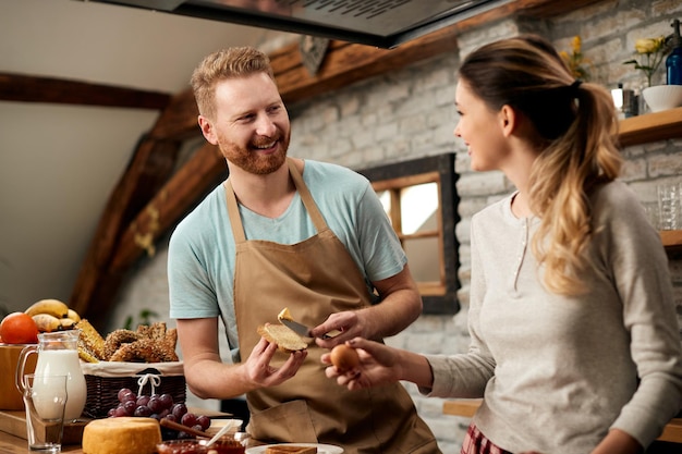 Free photo happy couple communicating while preparing food in the kitchen