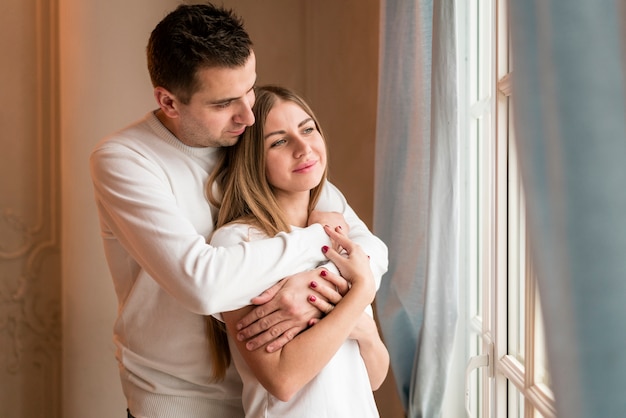 Free Photo happy couple embraced and looking through window