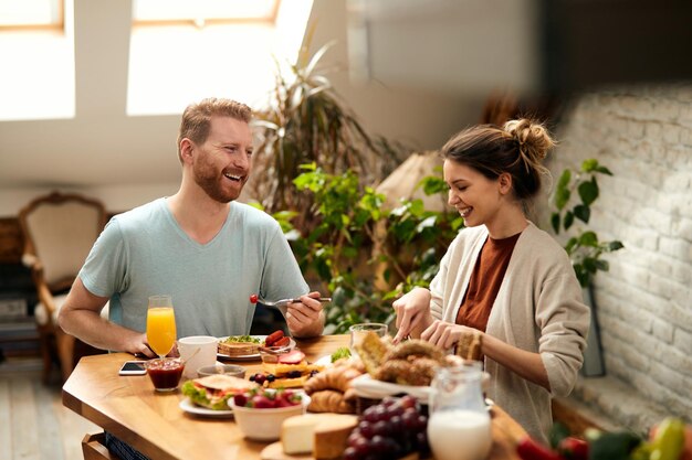 Happy couple enjoying in conversation while eating at dining table