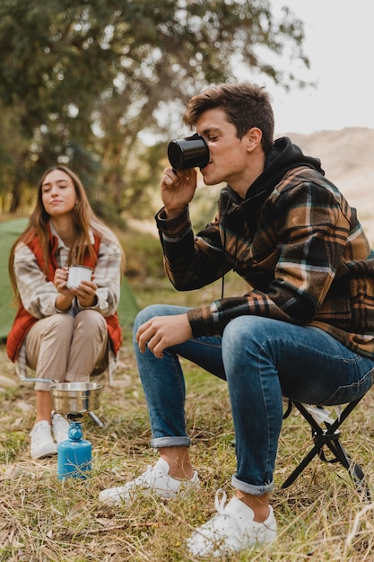 Happy couple in the forest drinking coffee