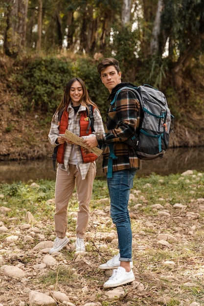 Happy couple in the forest holding a map long shot