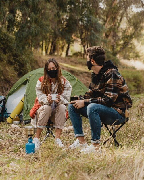 Happy couple in the forest wearing medical masks