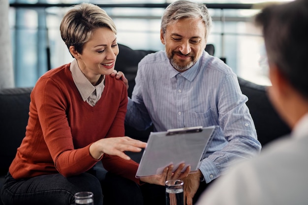 Happy couple going through terms of an agreement during a meeting with financial advisor