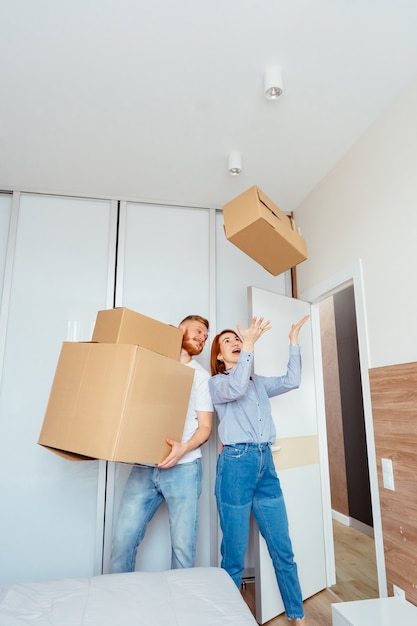 Happy couple holding cardboard boxes and moving to new place