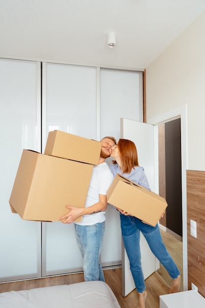 Happy couple holding cardboard boxes and moving to new place