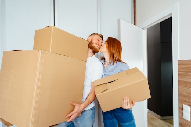 Free photo happy couple holding cardboard boxes and moving to new place