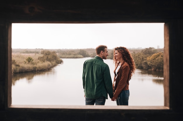 Free photo happy couple holding hands next to a pond