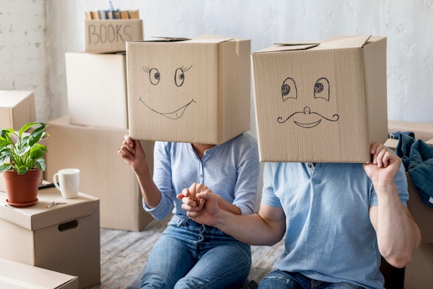 Free photo happy couple at home on moving day with boxes over heads