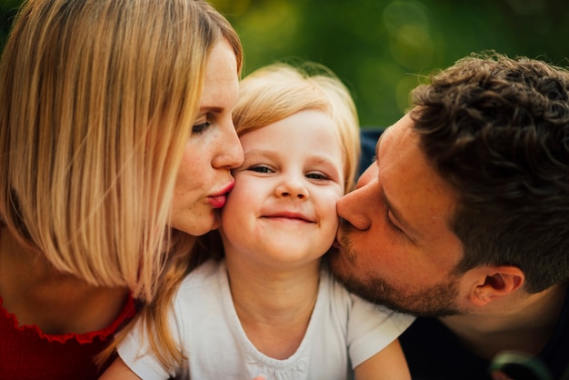 Free photo happy couple kissing their child close up