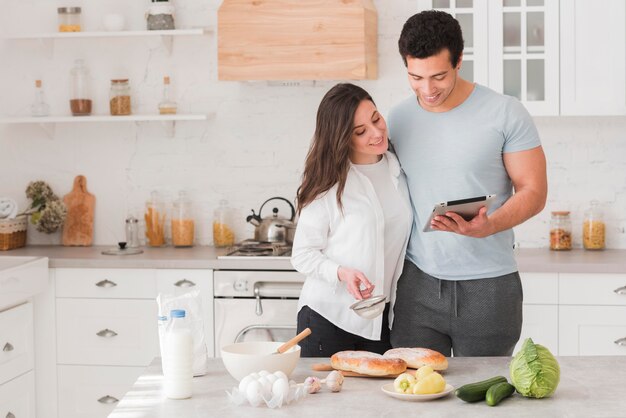 Happy couple learning how to cook from online recipes