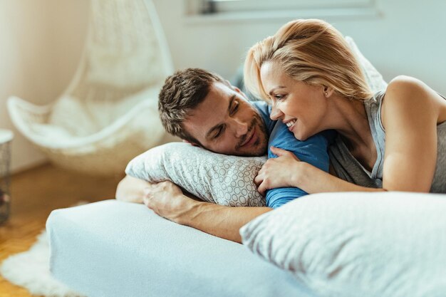 Happy couple in love talking while relaxing in bedroom in the morning