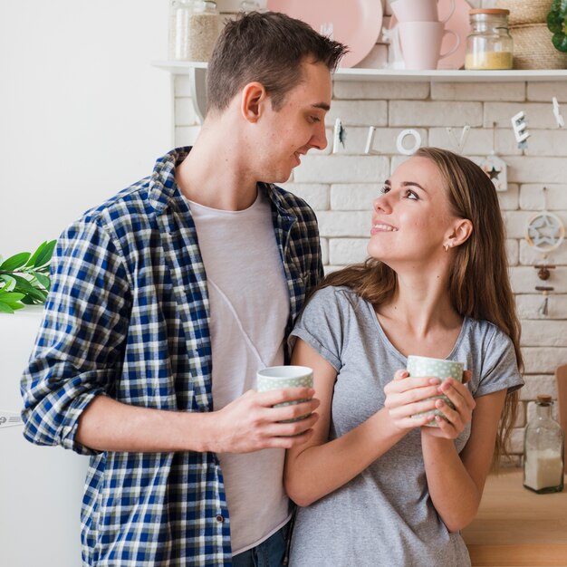 Happy couple in love together in kitchen looking to each other