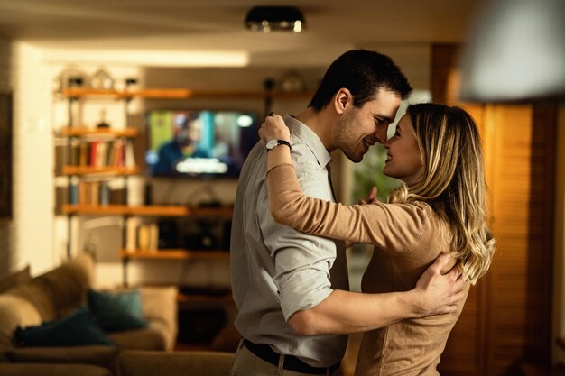 Happy couple in love touching noses while dancing at home