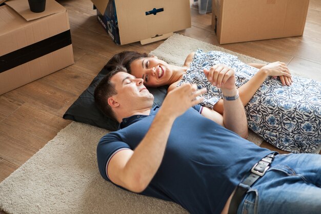 Happy couple lying on the floor after moving in .Woman and man smiling