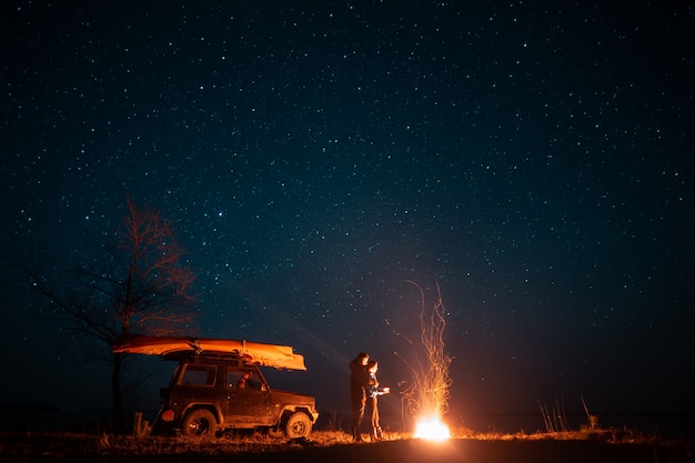 Free Photo happy couple man and woman standing in front burning bonfire