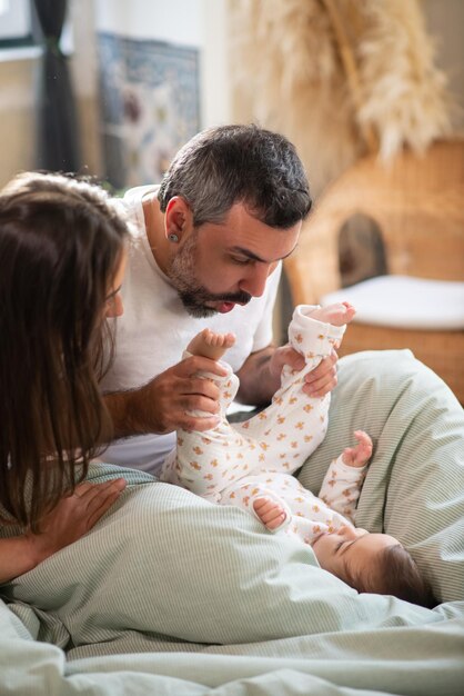 Happy couple playing with baby son in bed